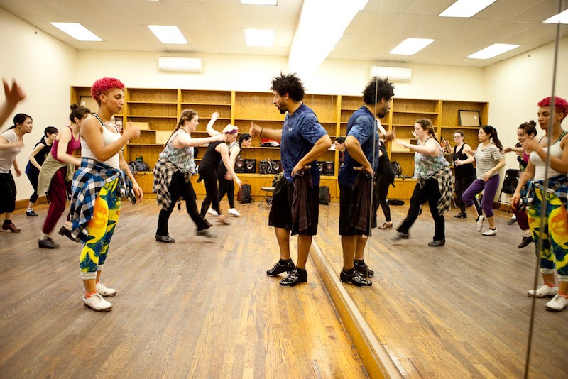 Jason Samuels Smith stands near a mirror as he observes a room full of tap students.